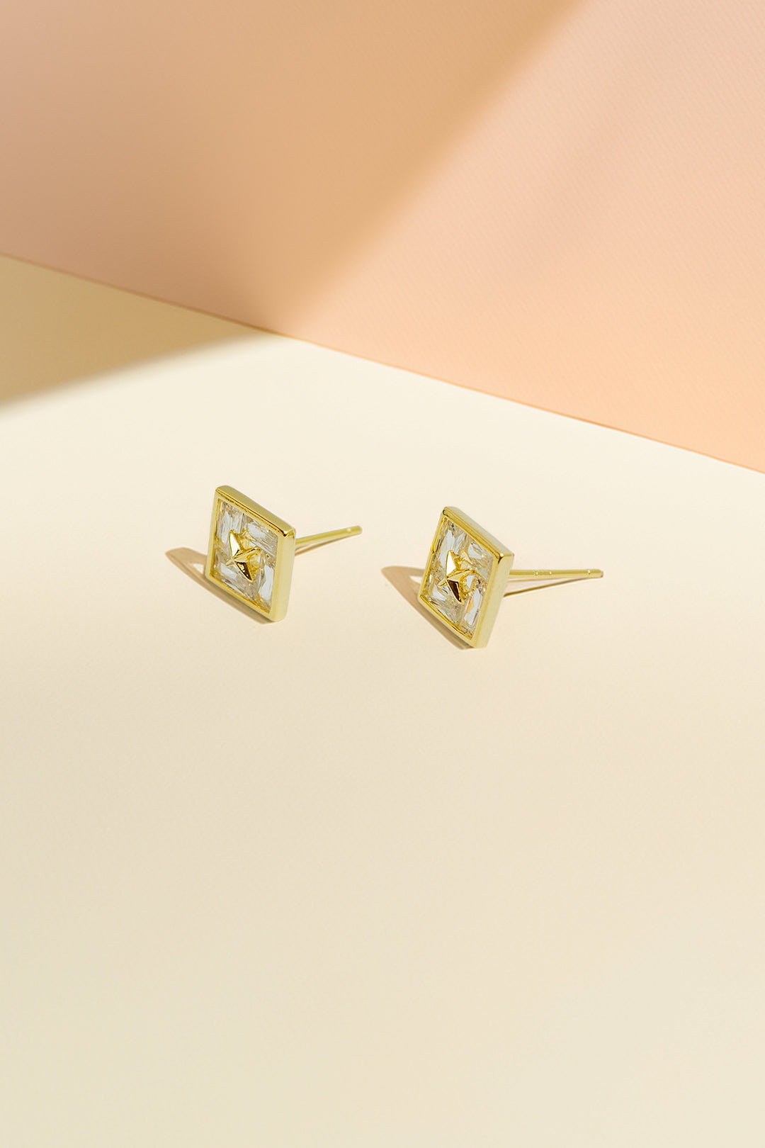 Gold-tone stud earrings on pastel background