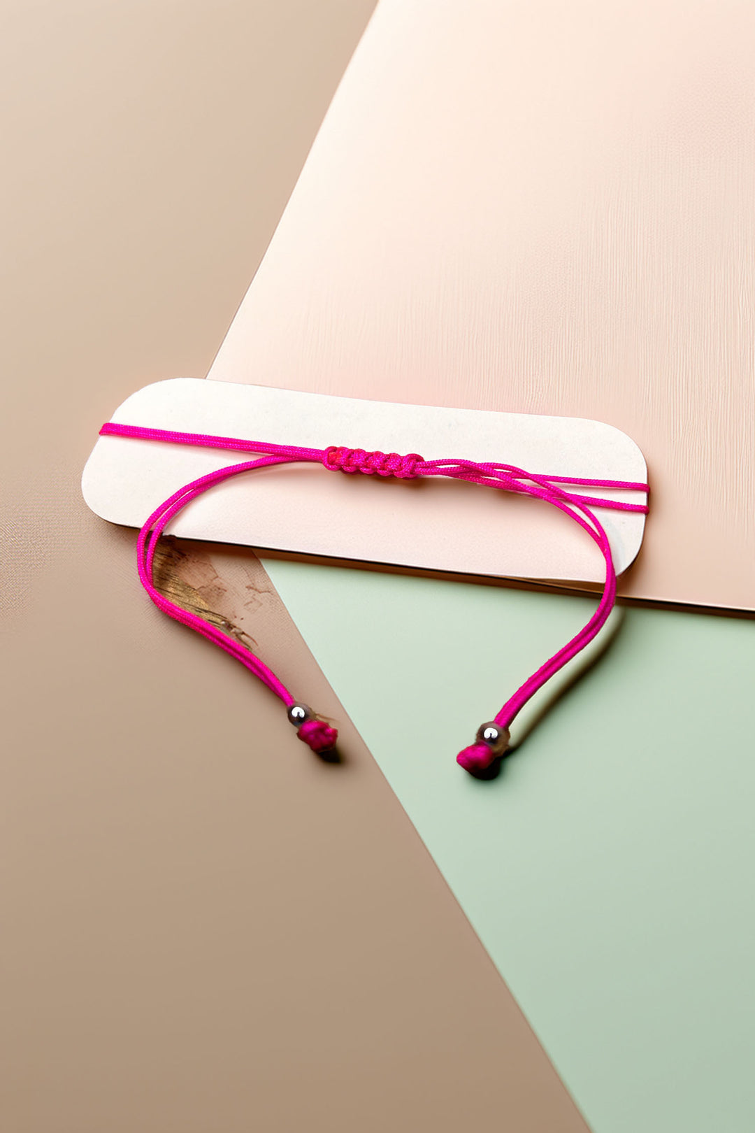 Pink cord bracelet on display with minimalist background