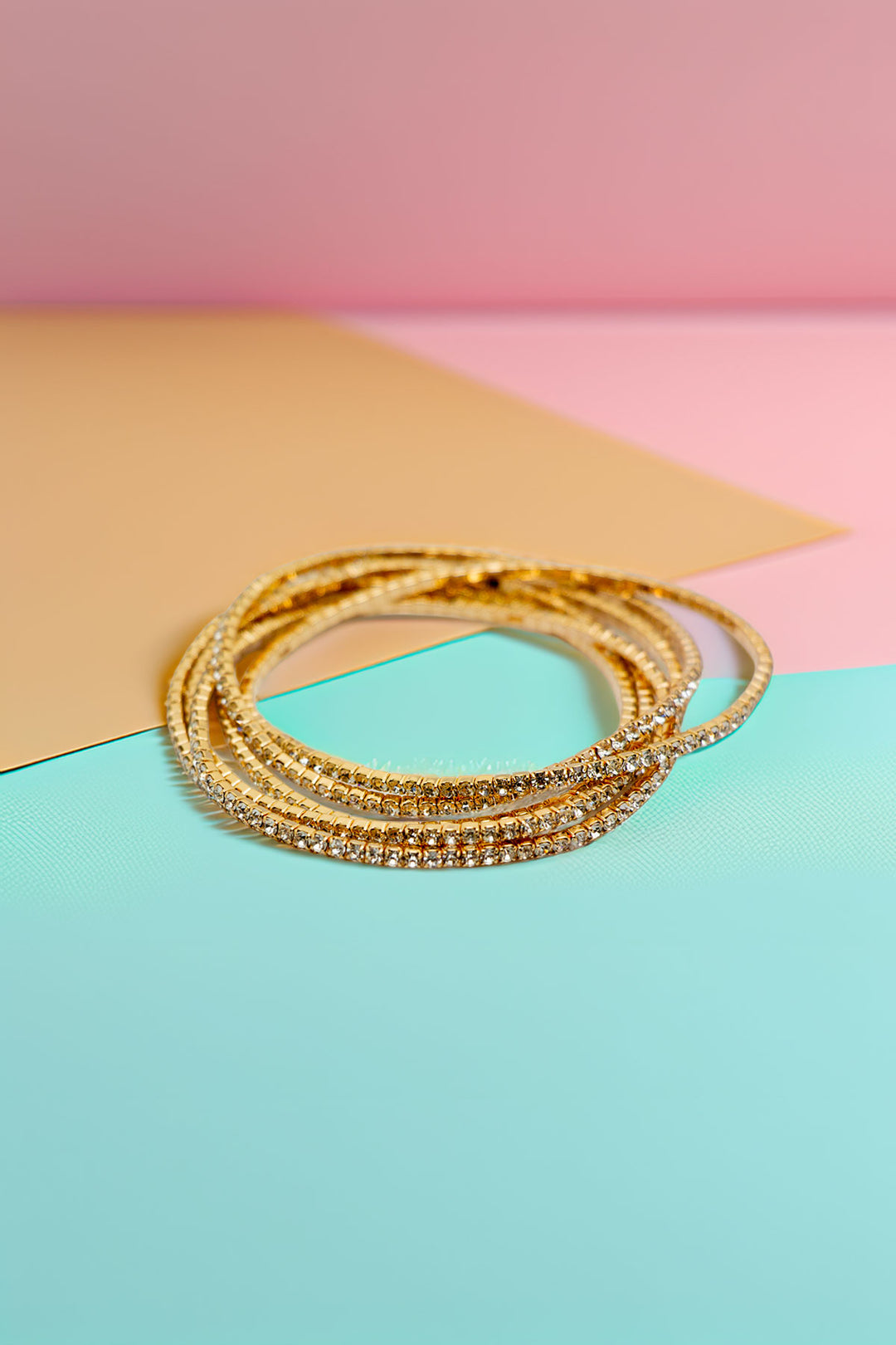Gold-tone rhinestone bracelets on colorful background