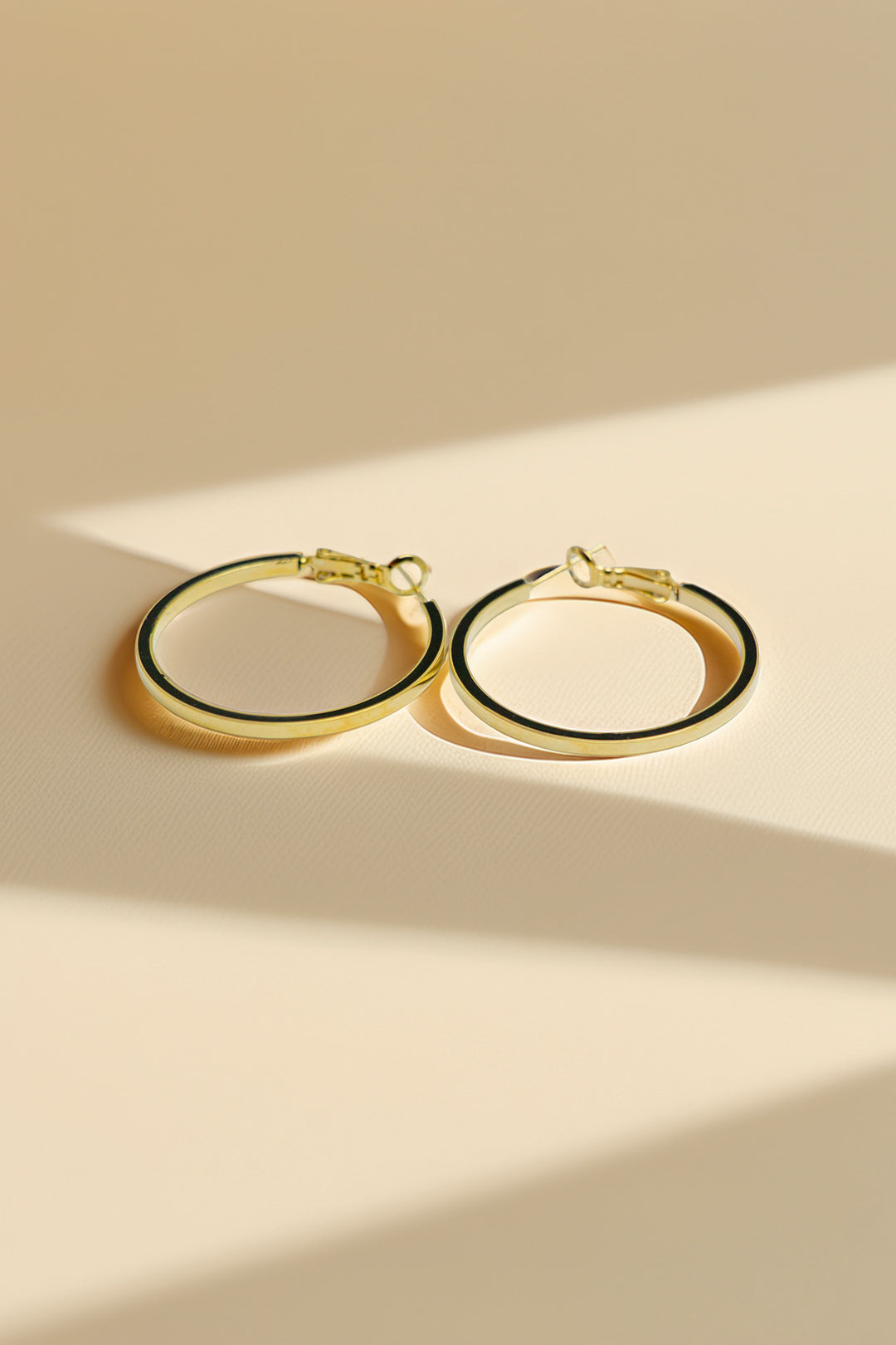 Pair of gold hoop earrings on a beige background