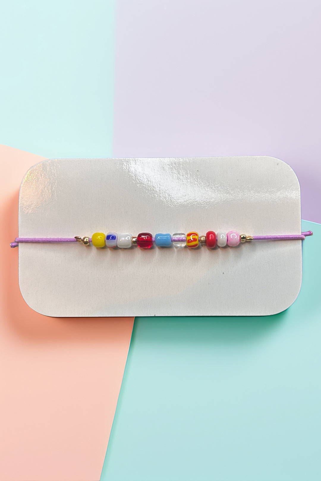 Front view of a colorful beaded bracelet with various beads on a purple string.