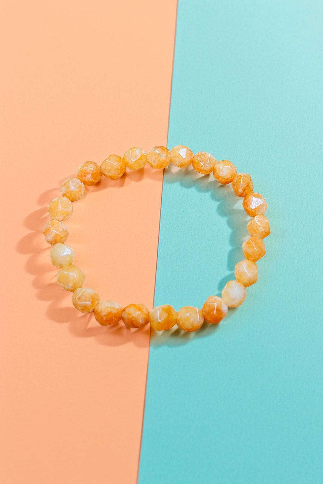 Orange beaded bracelet on two-toned background