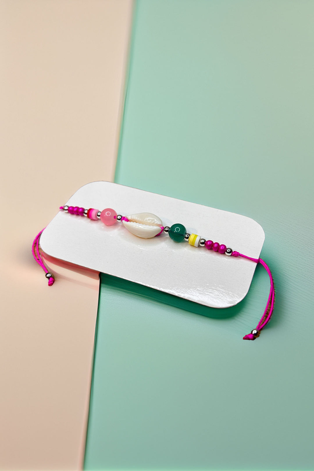 Top view of colorful beaded friendship bracelet with pink, green, and shell beads