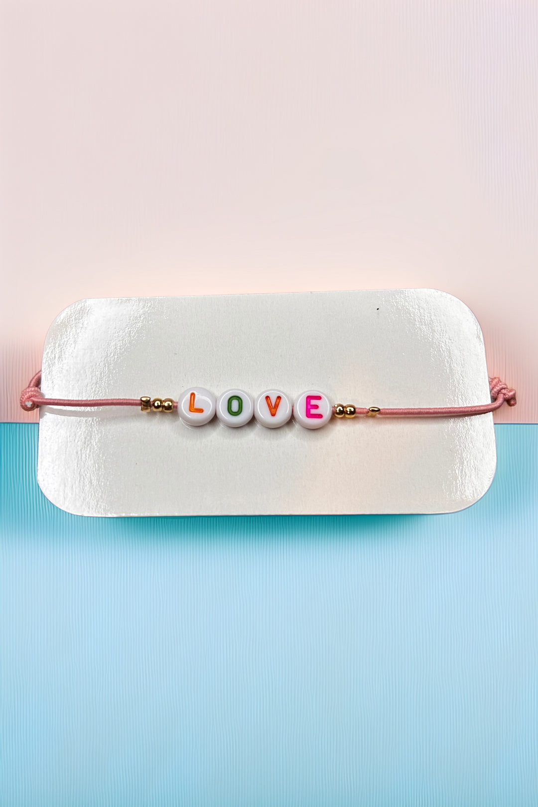 Love beaded bracelet with pink cord on display card