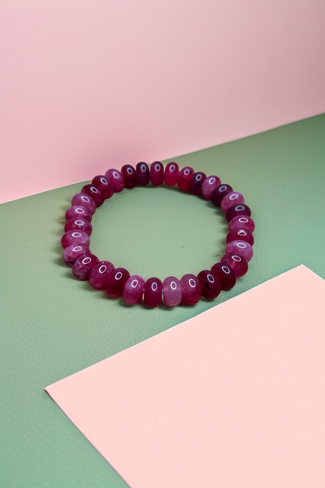 Ruby red beaded bracelet on pink and green background