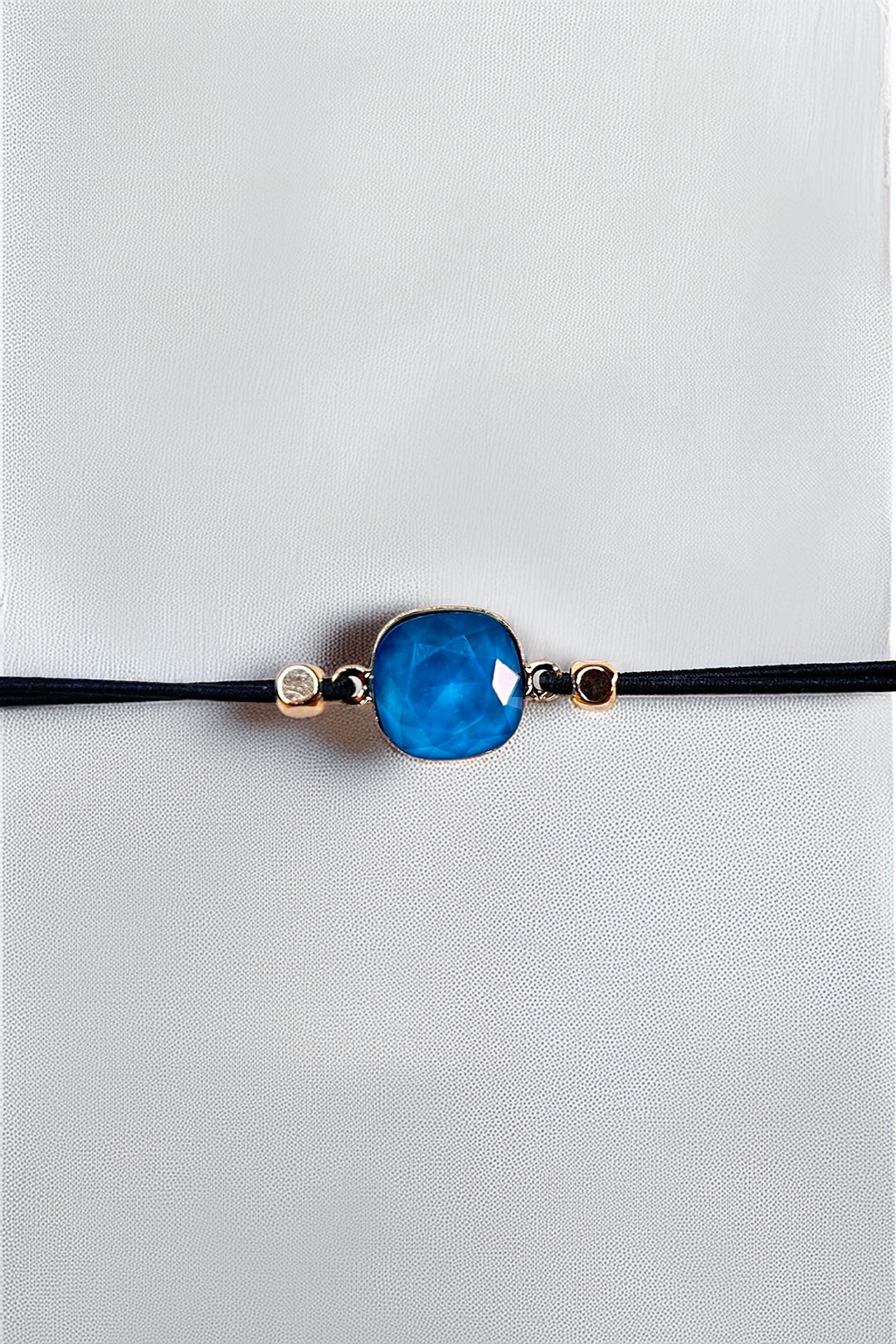 Close-up of blue stone bracelet on black cord