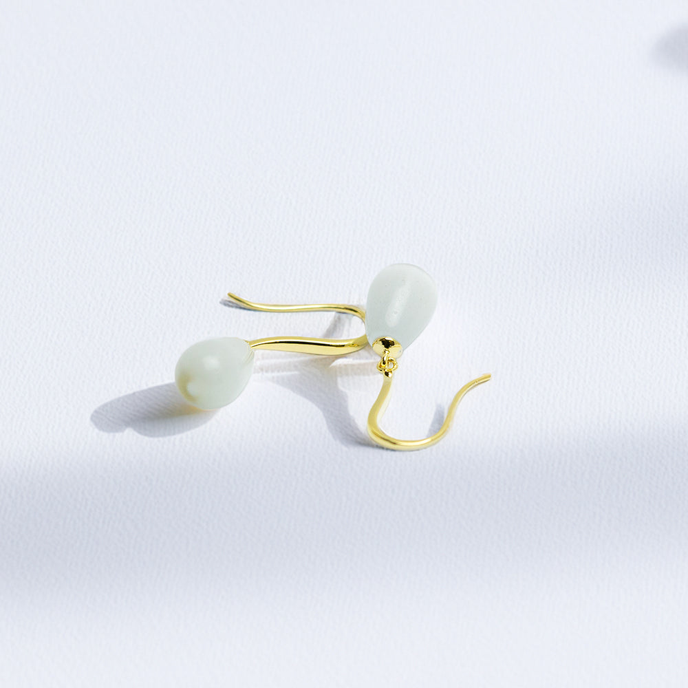Elegant gold and pearl teardrop earrings on white background