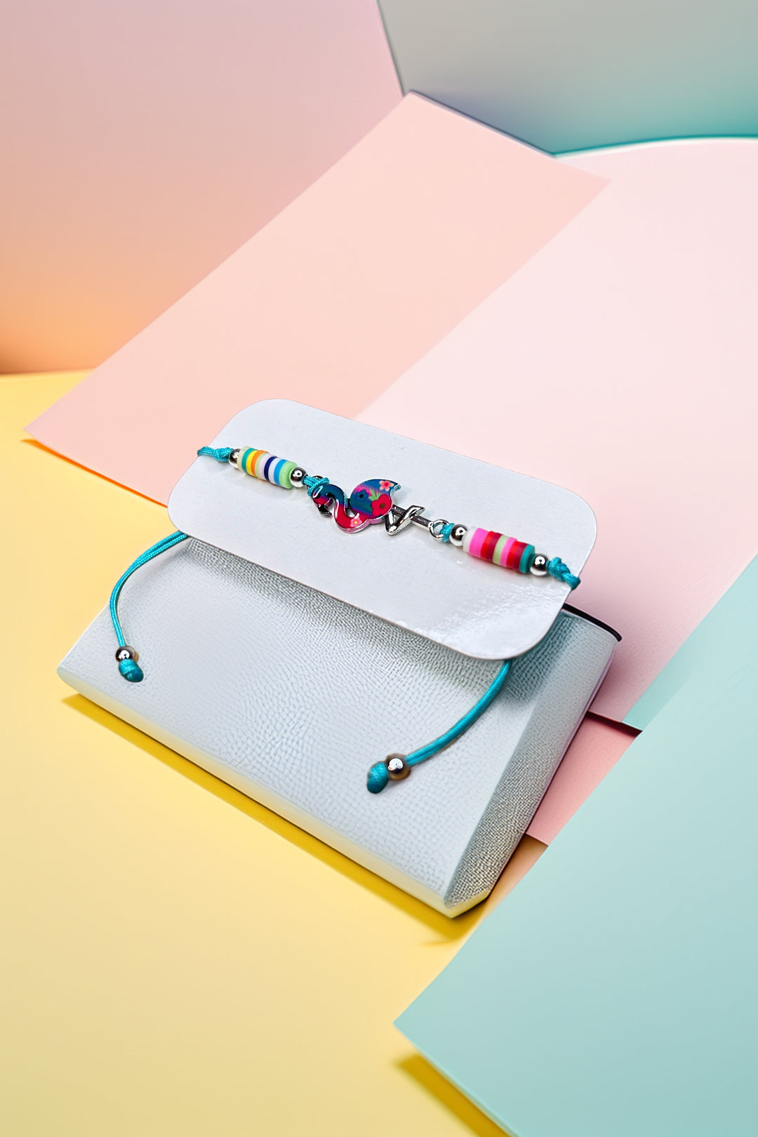 Colorful friendship bracelet with love charm on packaging in pastel background