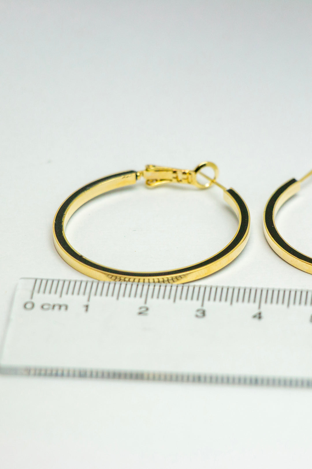 Close-up of gold hoop earrings with a ruler