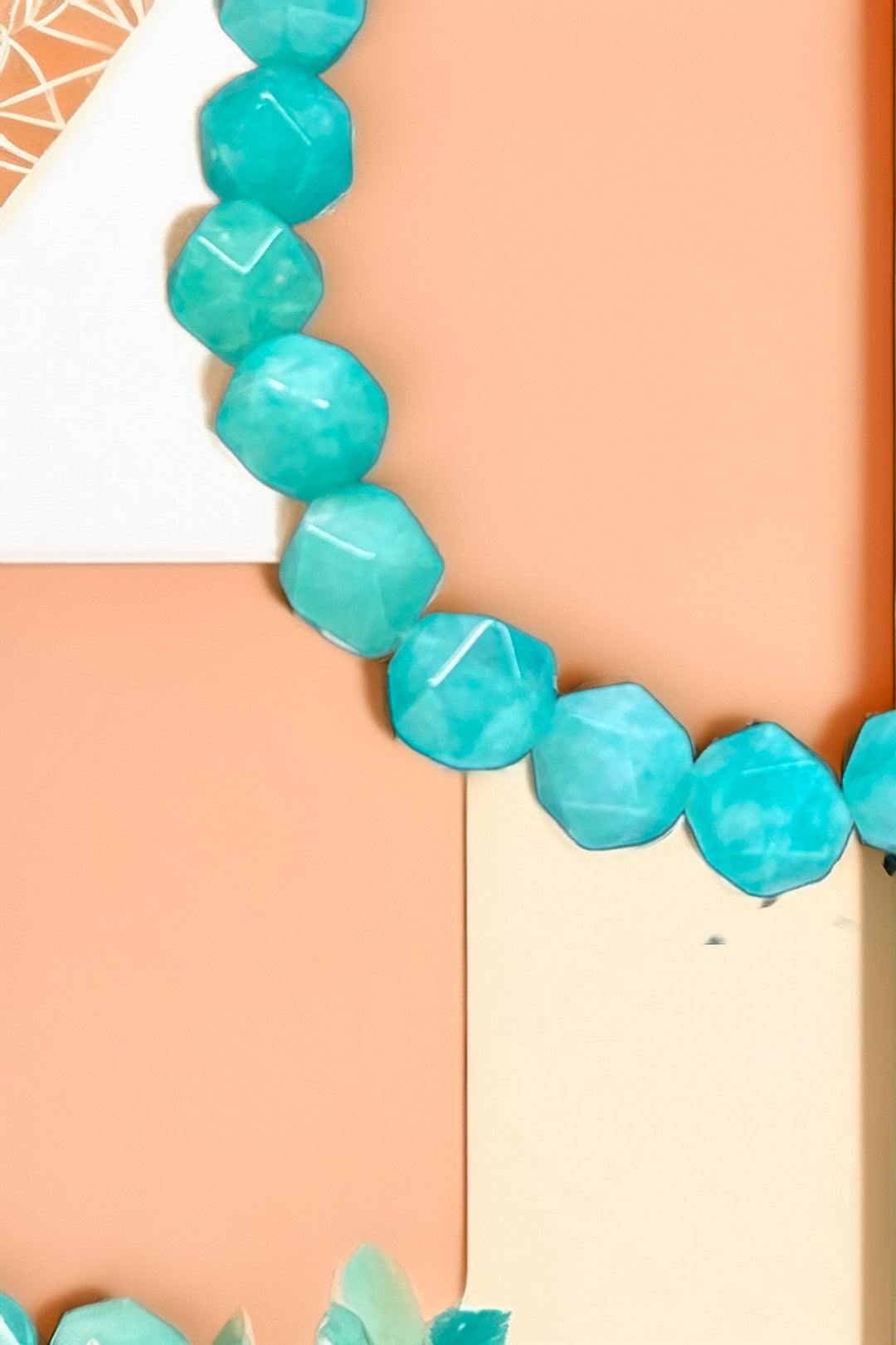 Side view of turquoise beaded bracelet on peach background