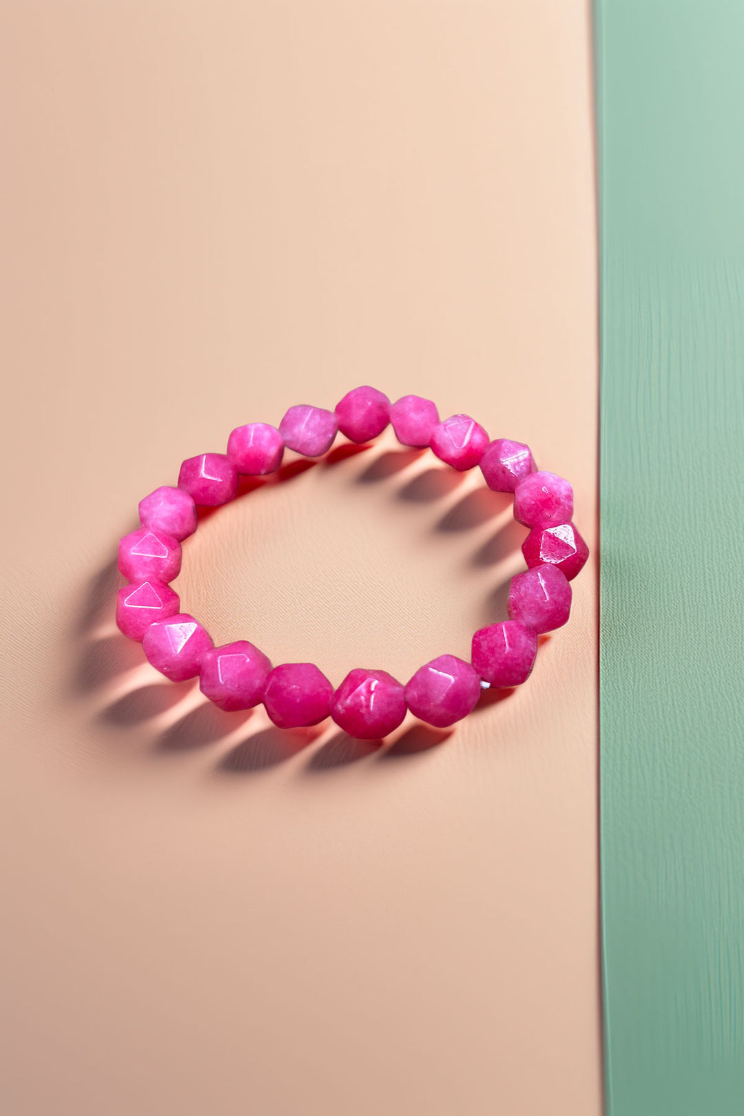 Angled side view of pink beaded bracelet on soft backdrop