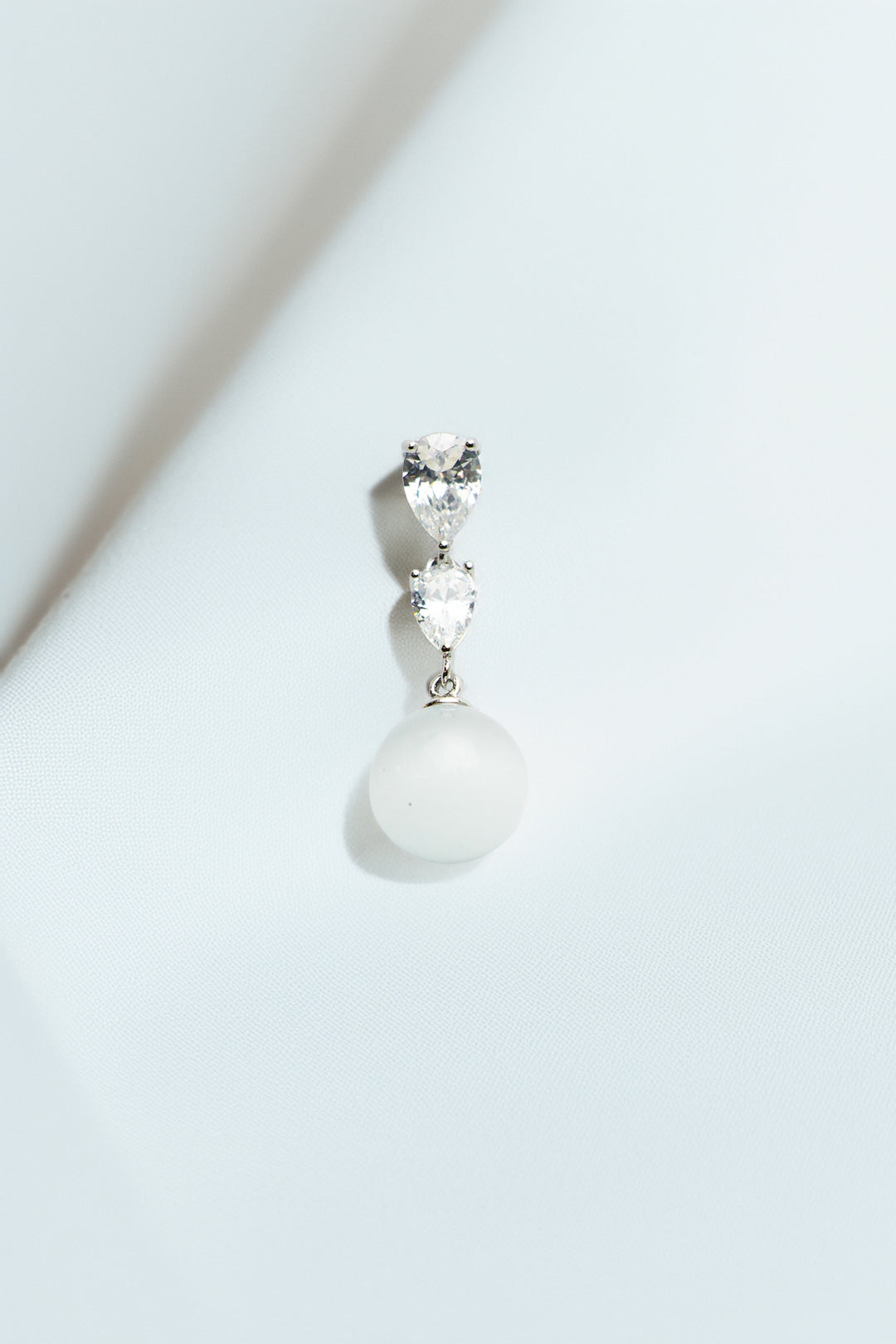 Single earring on a soft white drape