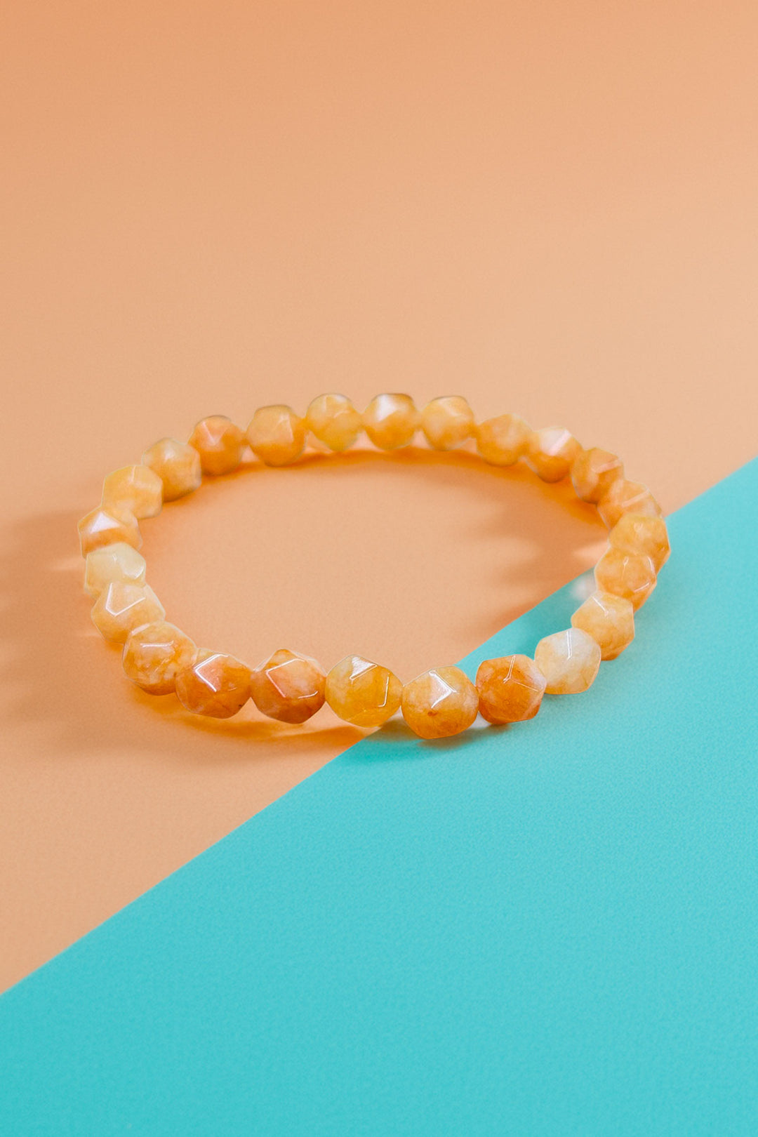 Orange bracelet on teal and peach backdrop