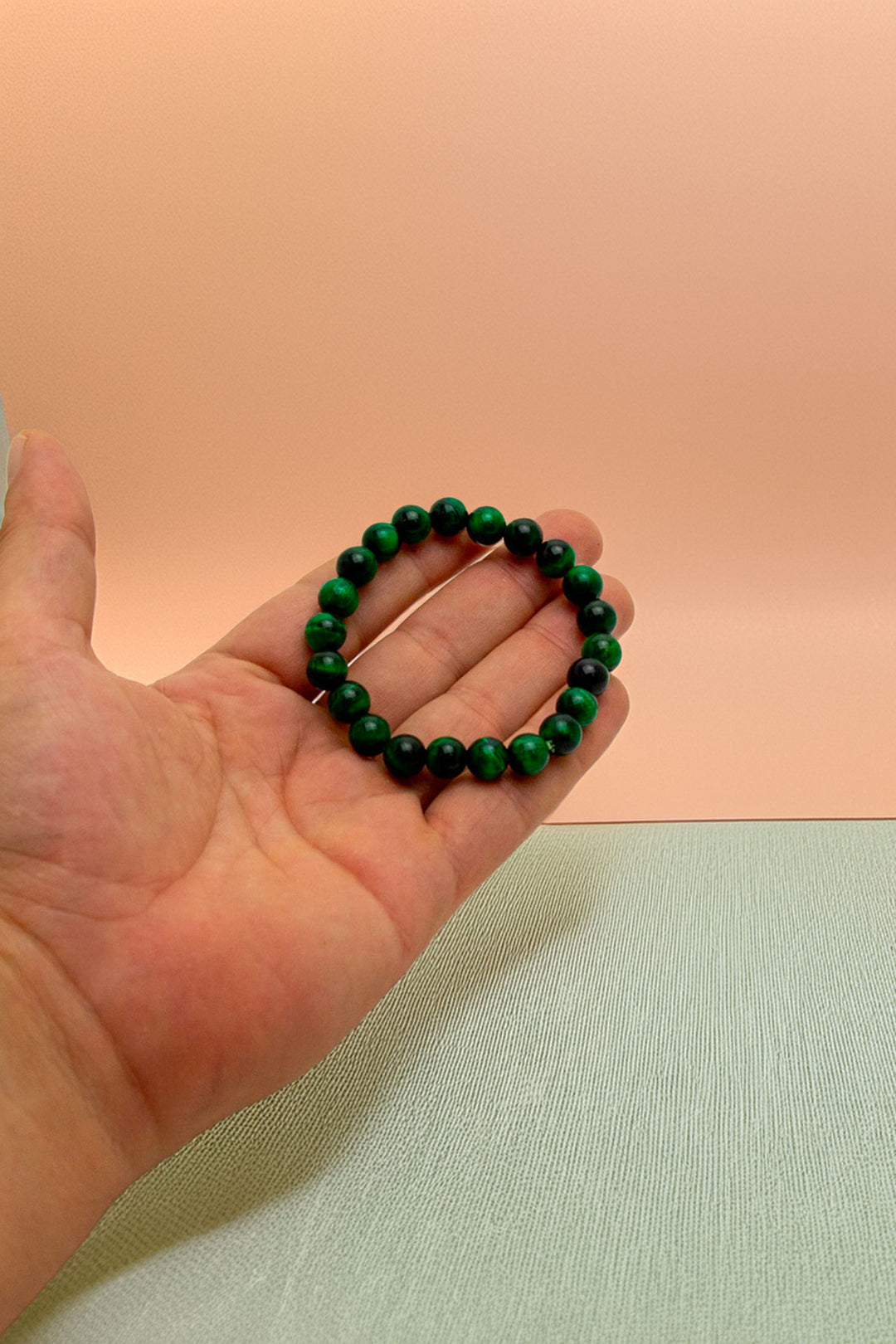 Holding green beaded bracelet in hand for size perspective