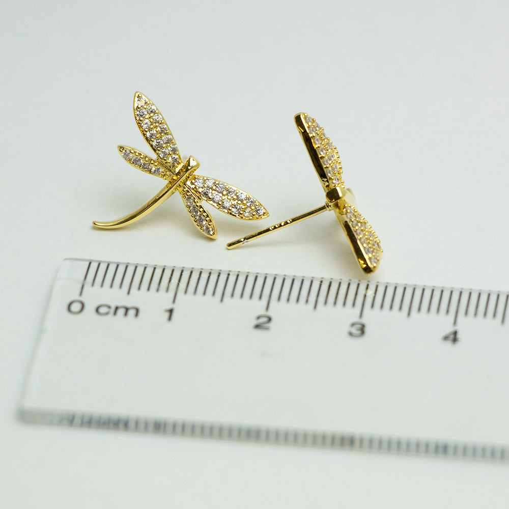 Gold dragonfly earrings next to a ruler