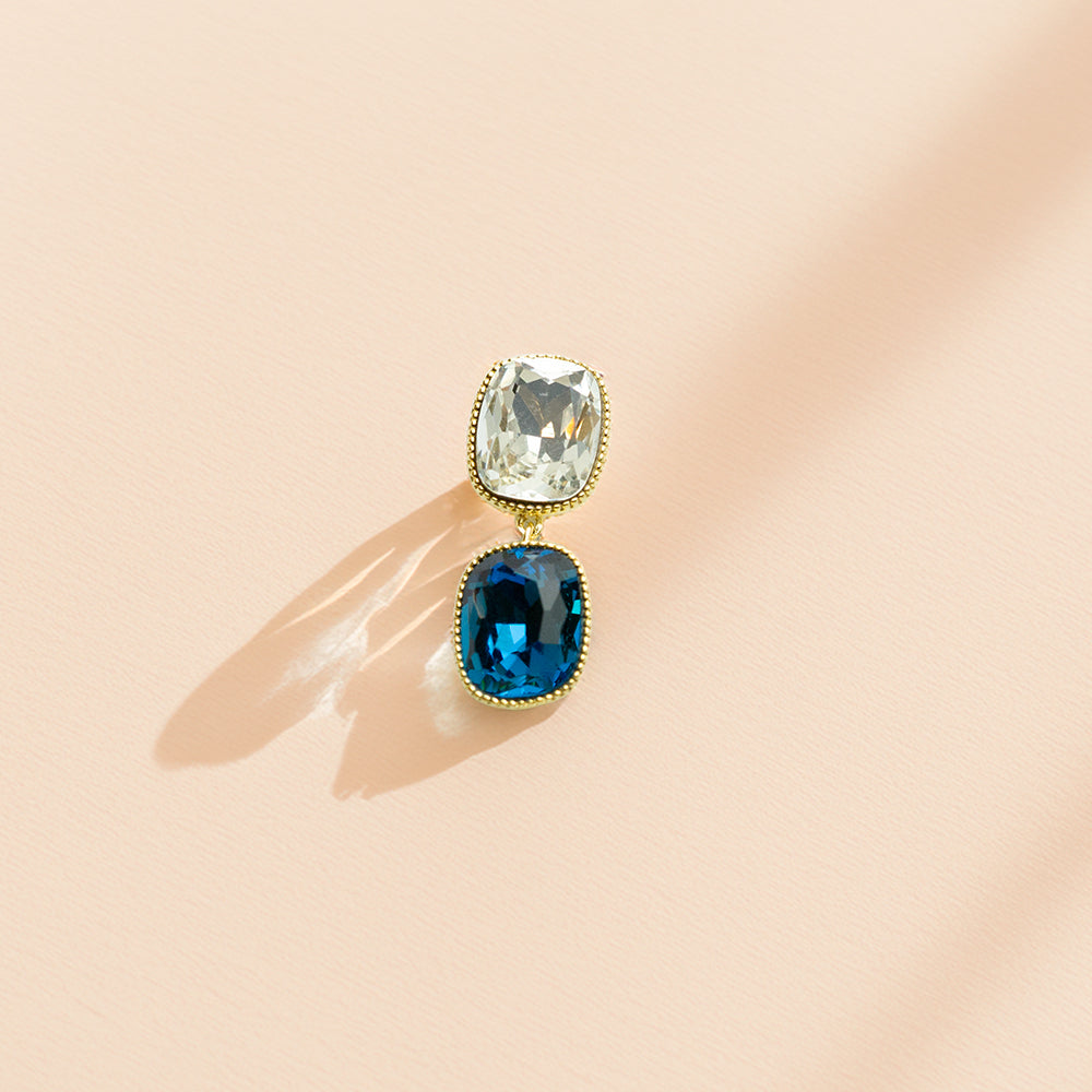 Single piece view of crystal earrings on a peach background