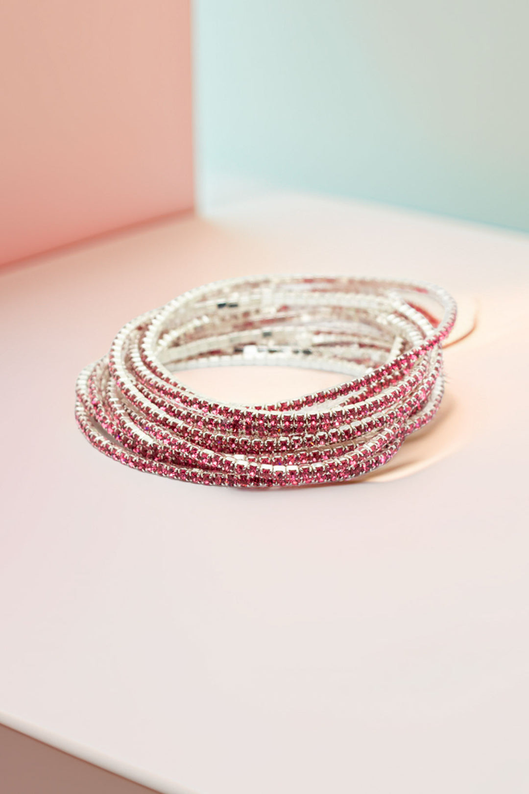 Stack of rhinestone bangles on pastel background