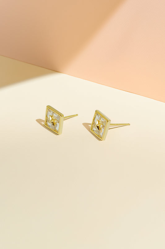 Gold-tone stud earrings on pastel background