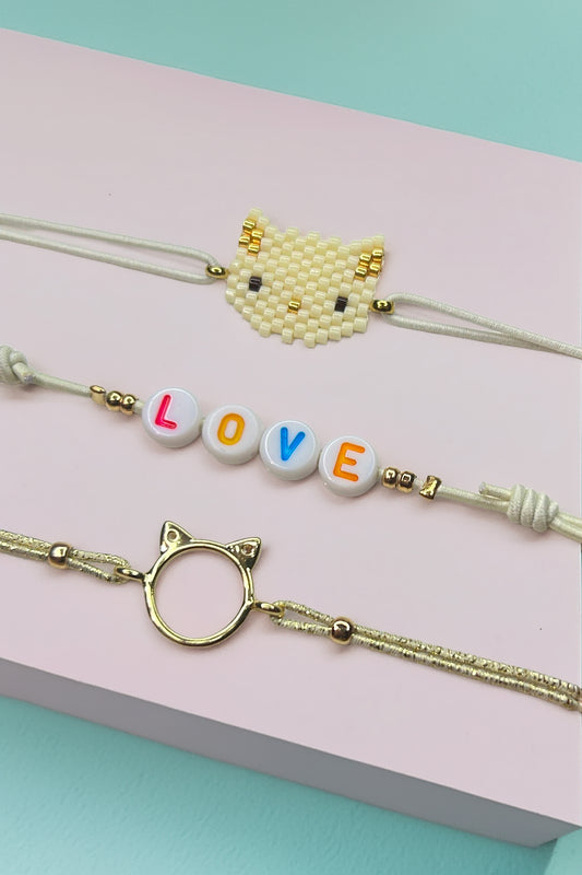 Close-up of cat-themed bracelet set on pastel background