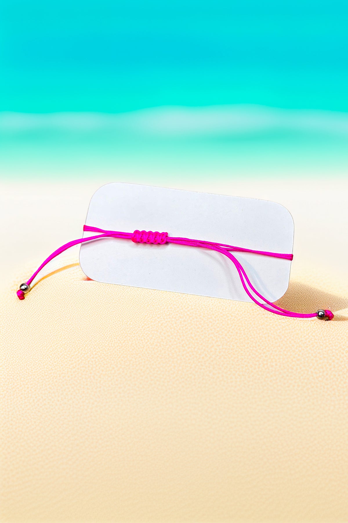Vibrant pink string bracelet on display card