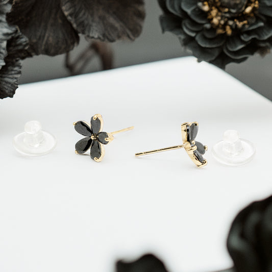 Black floral stud earrings with gold frame on display