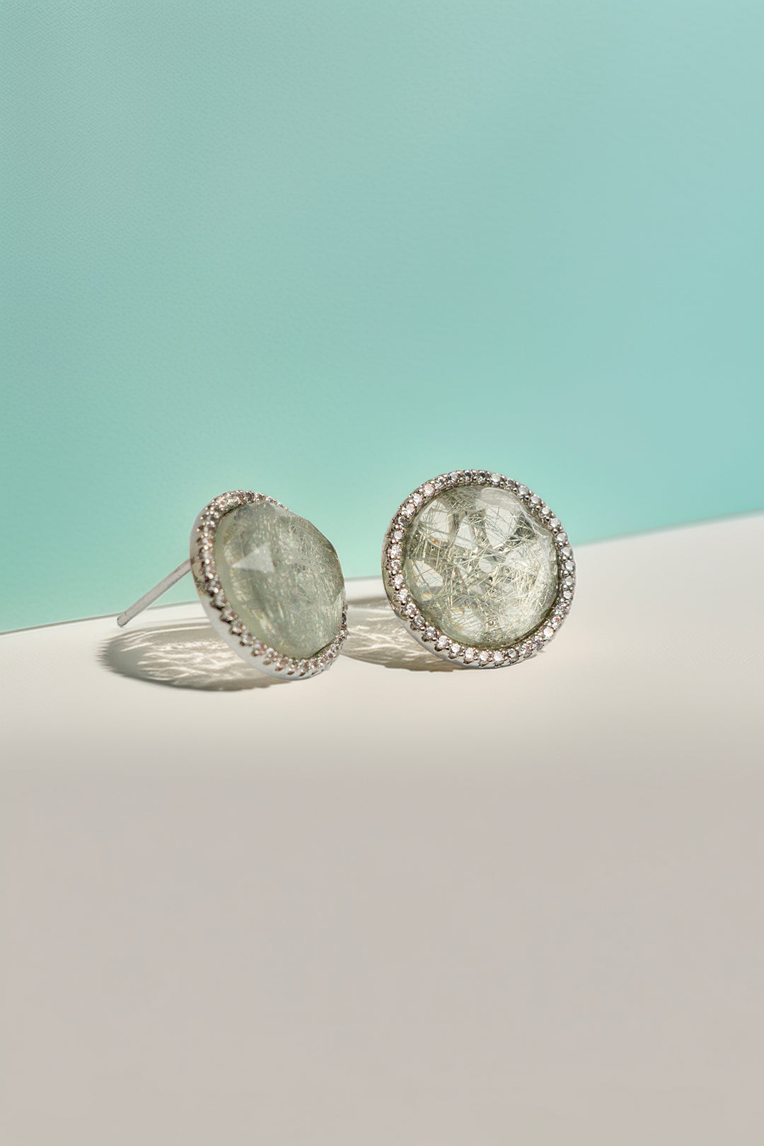 Quartz stud earrings on turquoise background