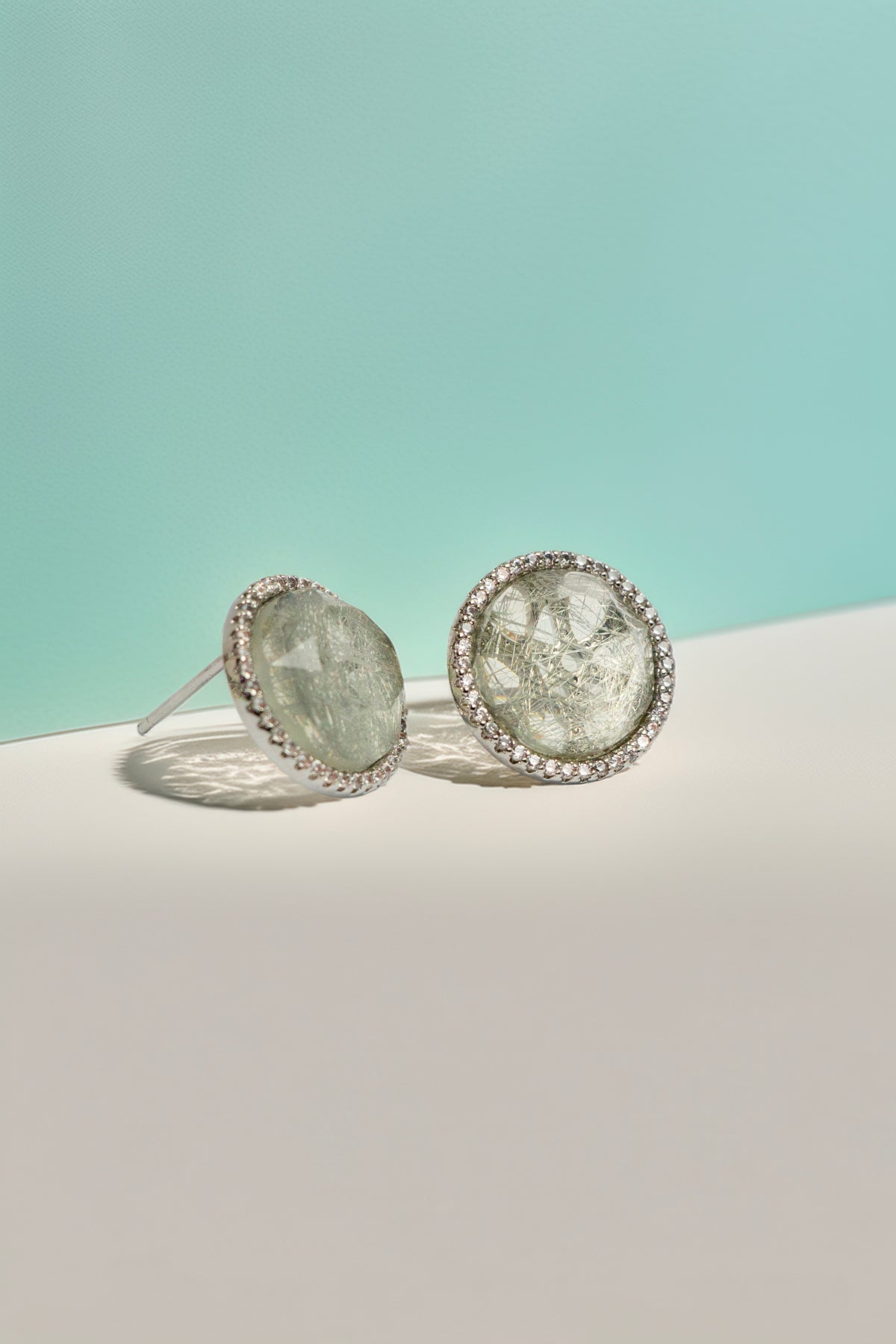 Quartz stud earrings on turquoise background