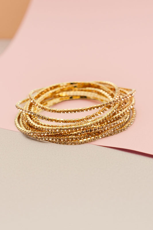 Stack of 12 sparkling gold-tone rhinestone bangles on display
