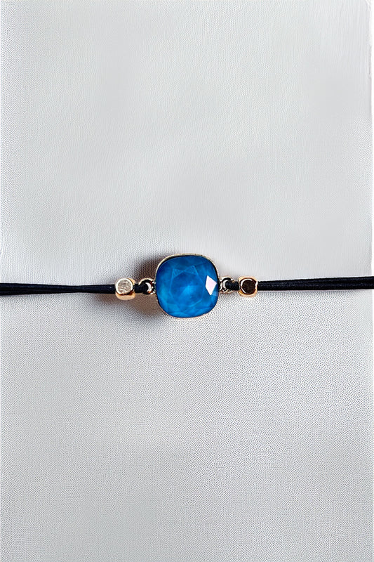 Close-up of blue stone bracelet on black cord