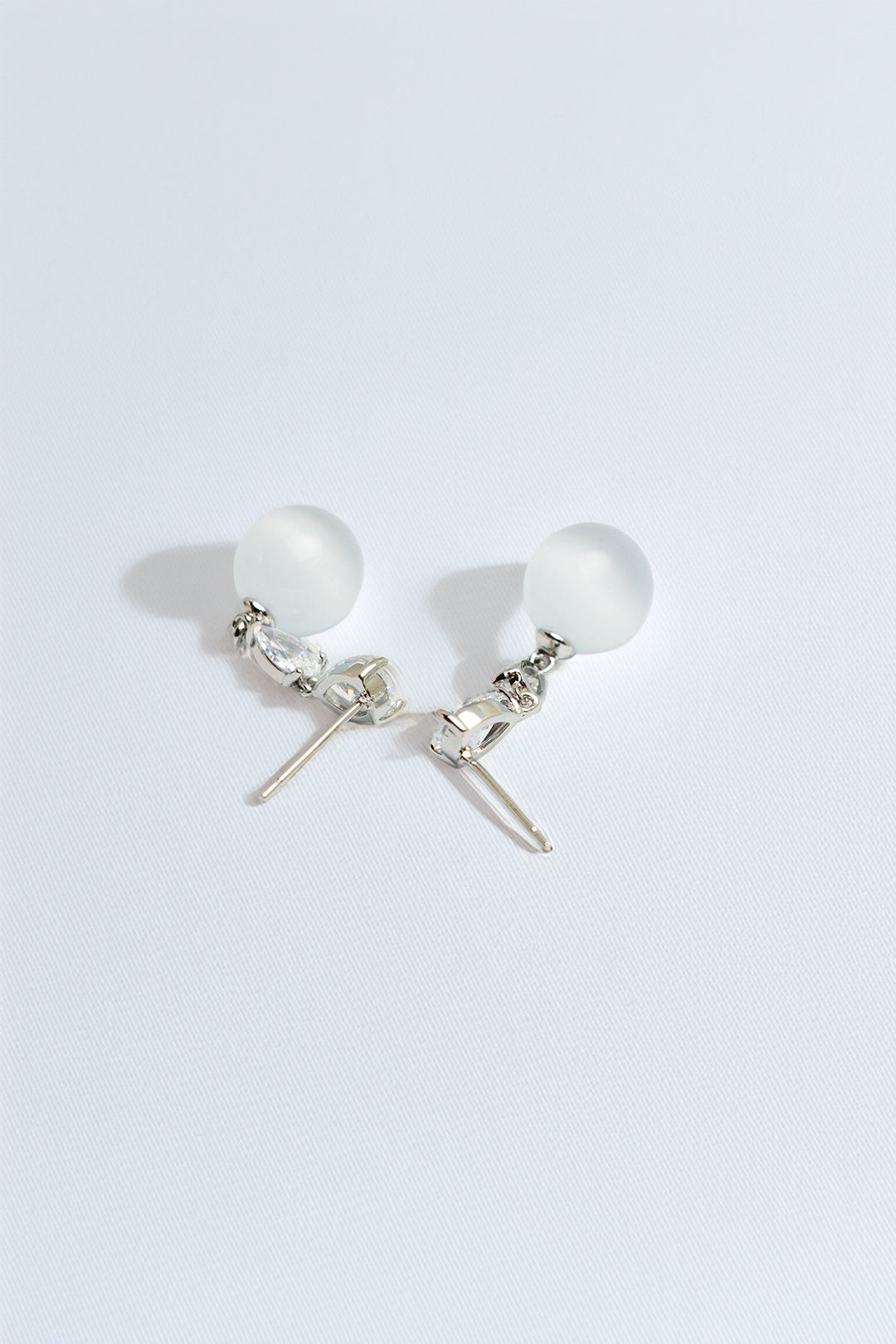 Close-up view of pearl and crystal drop earrings on white background