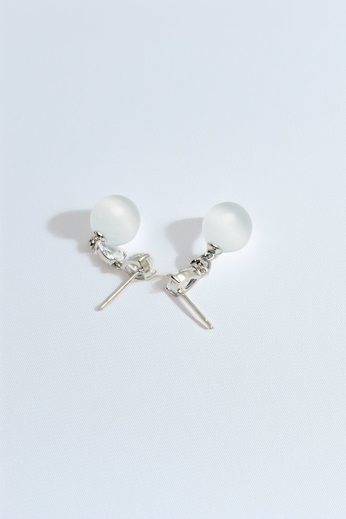 Close-up view of pearl and crystal drop earrings on white background