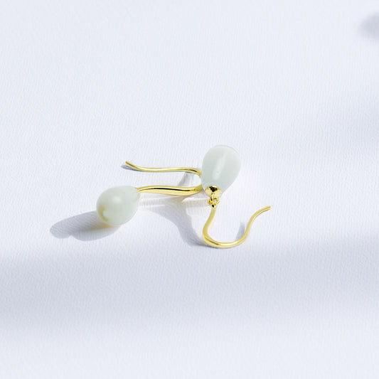 Elegant gold and pearl teardrop earrings on white background