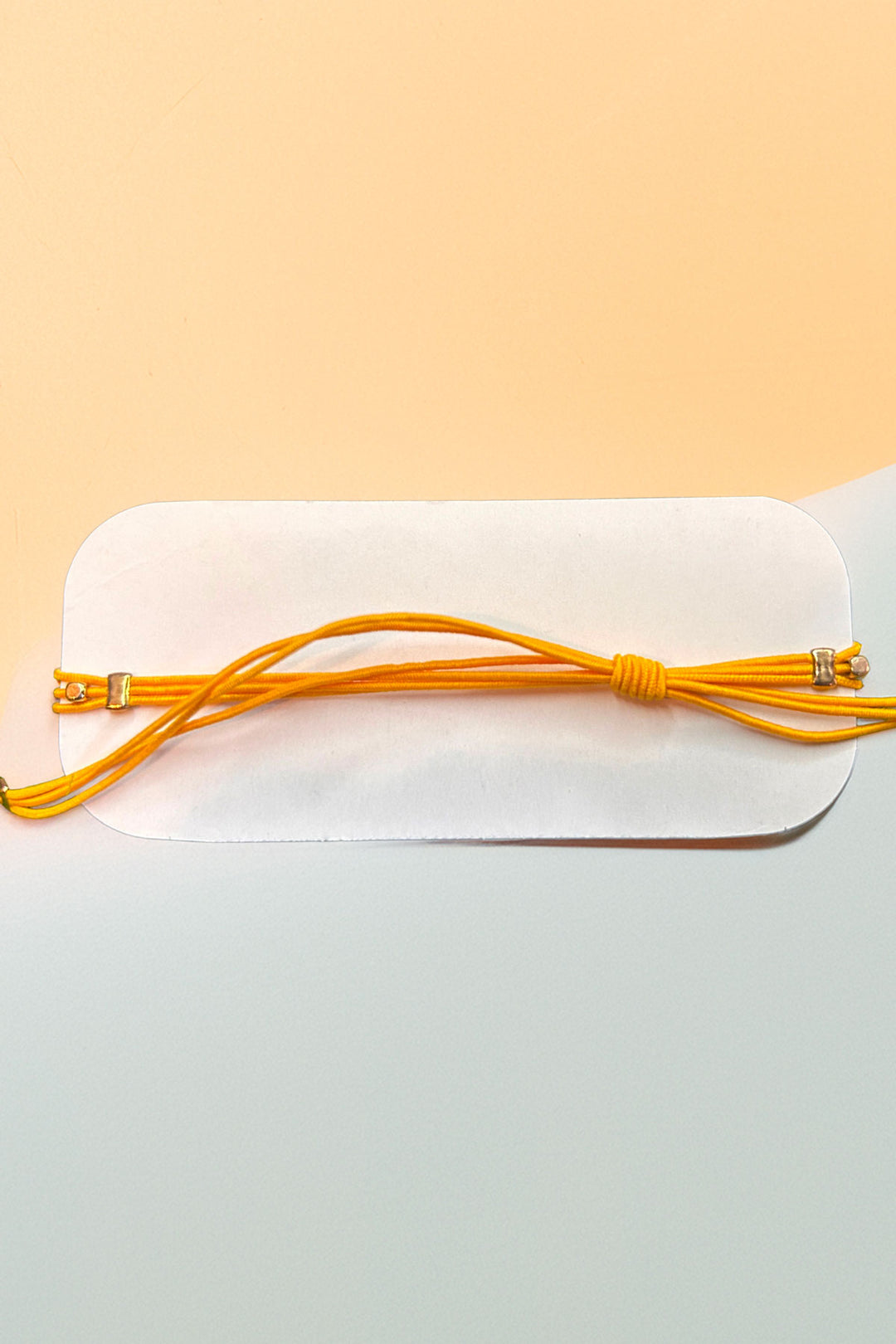 Back view of an adjustable yellow bracelet on card