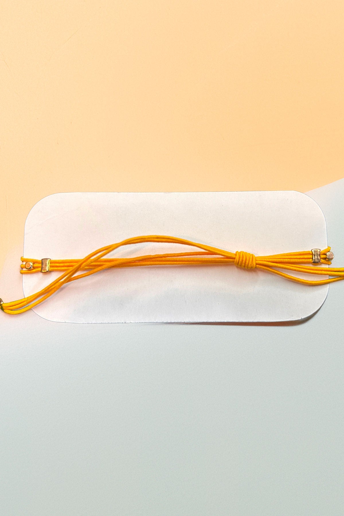 Back view of an adjustable yellow bracelet on card