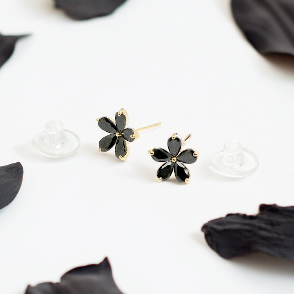 Close-up of black floral stud earrings with petals