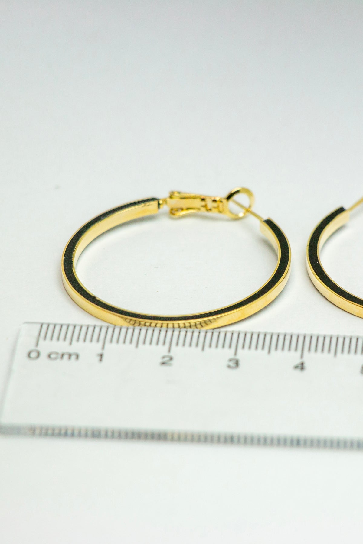 Close-up of gold hoop earrings with a ruler