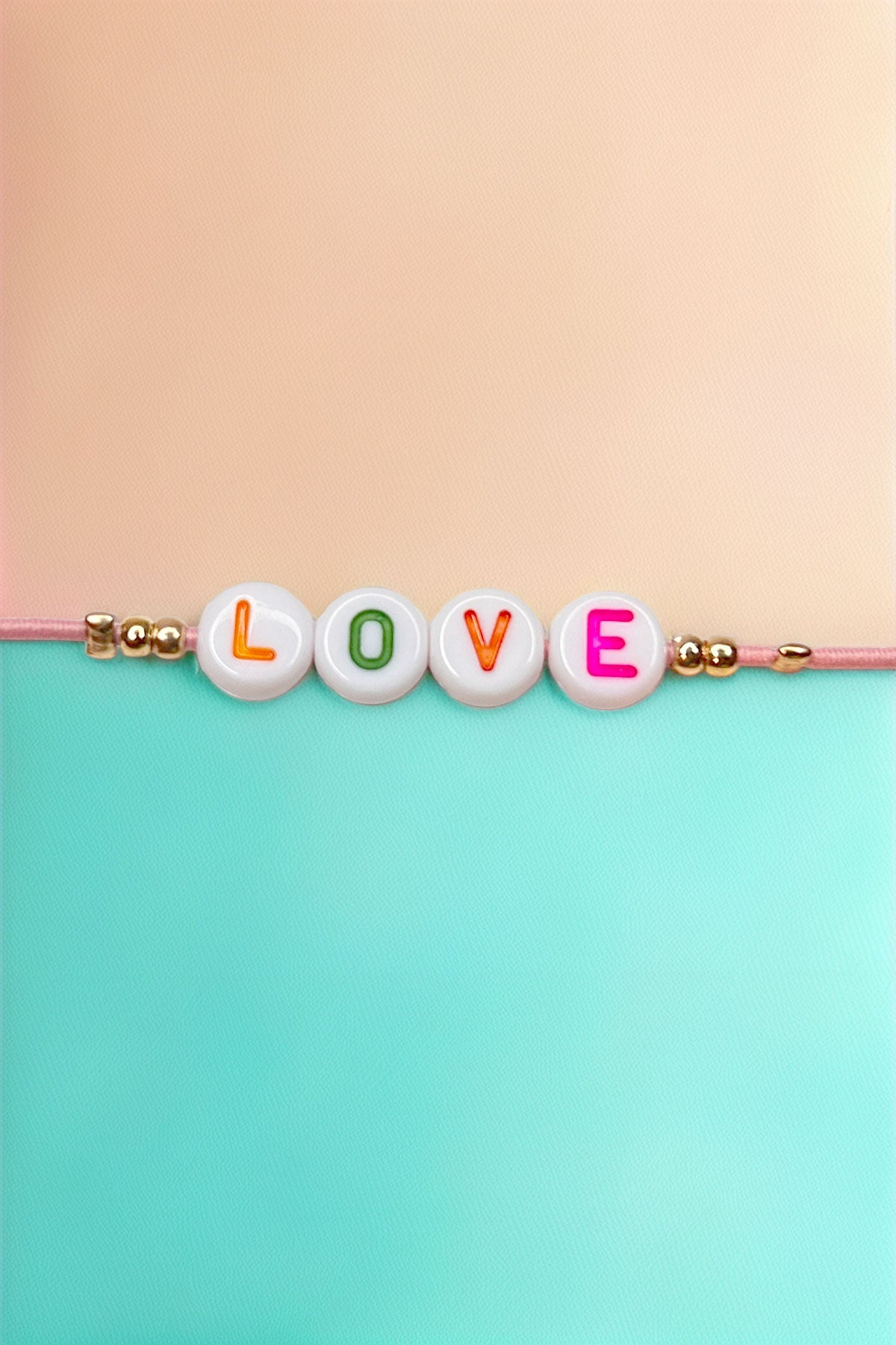 Close-up of 'LOVE' beads on bracelet with pastel colors.