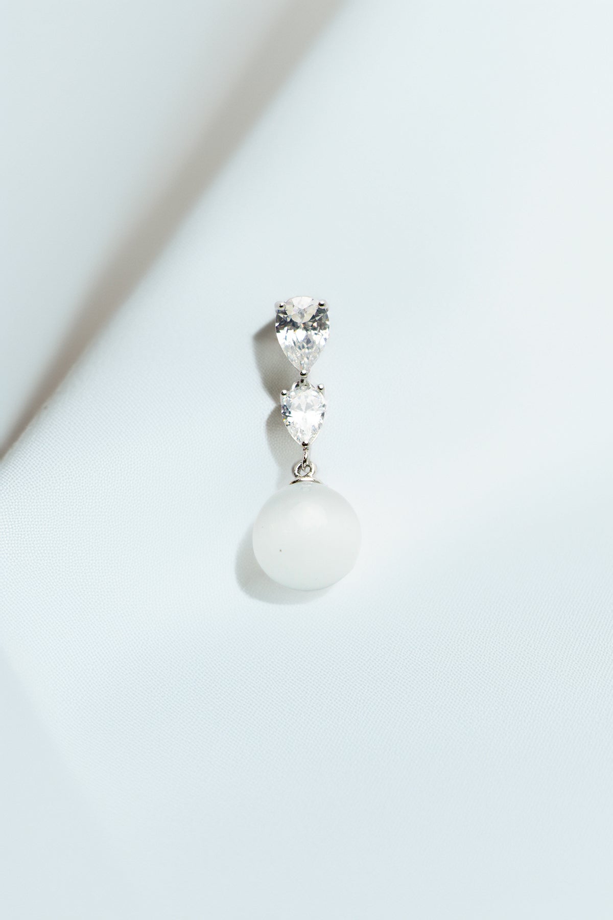 Single earring on a soft white drape