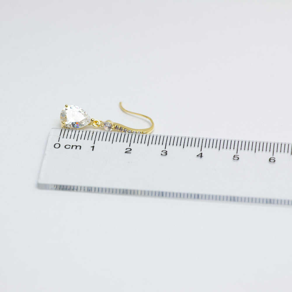 Gold dangle earring measured with a ruler