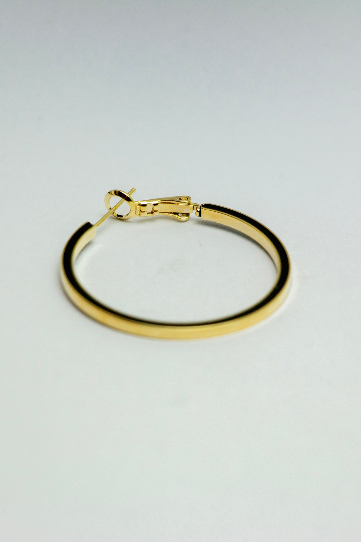 Single gold hoop earring in a stand-alone view